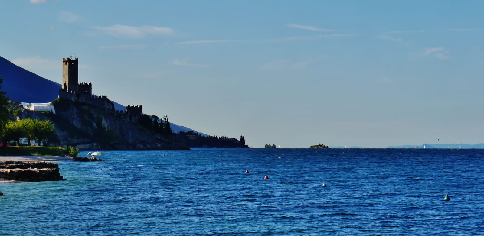 Blick über den Gardasee auf Malcesine mit dem Castello Scaligero am Ufer