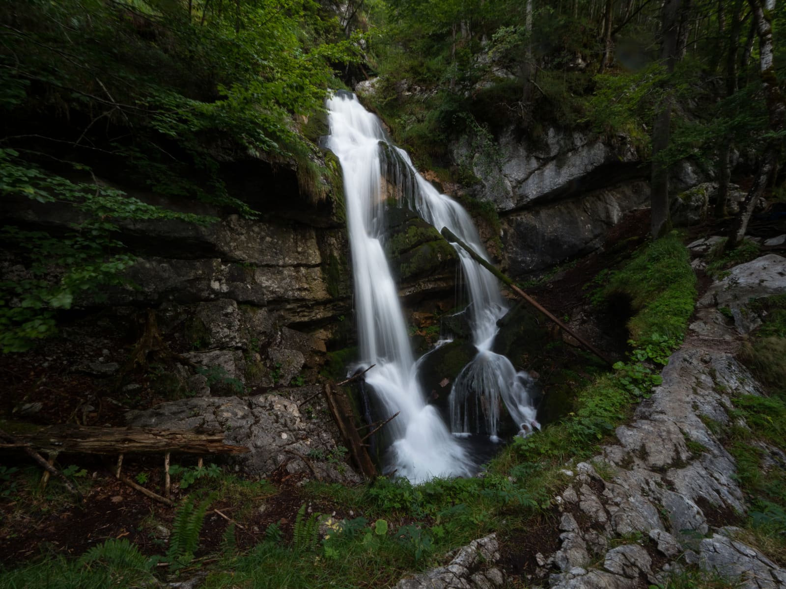 Schrainbachfall am Königssee mit mehreren weißen Kaskaden zwischen dunklen Felsen und dichtem Bergwald