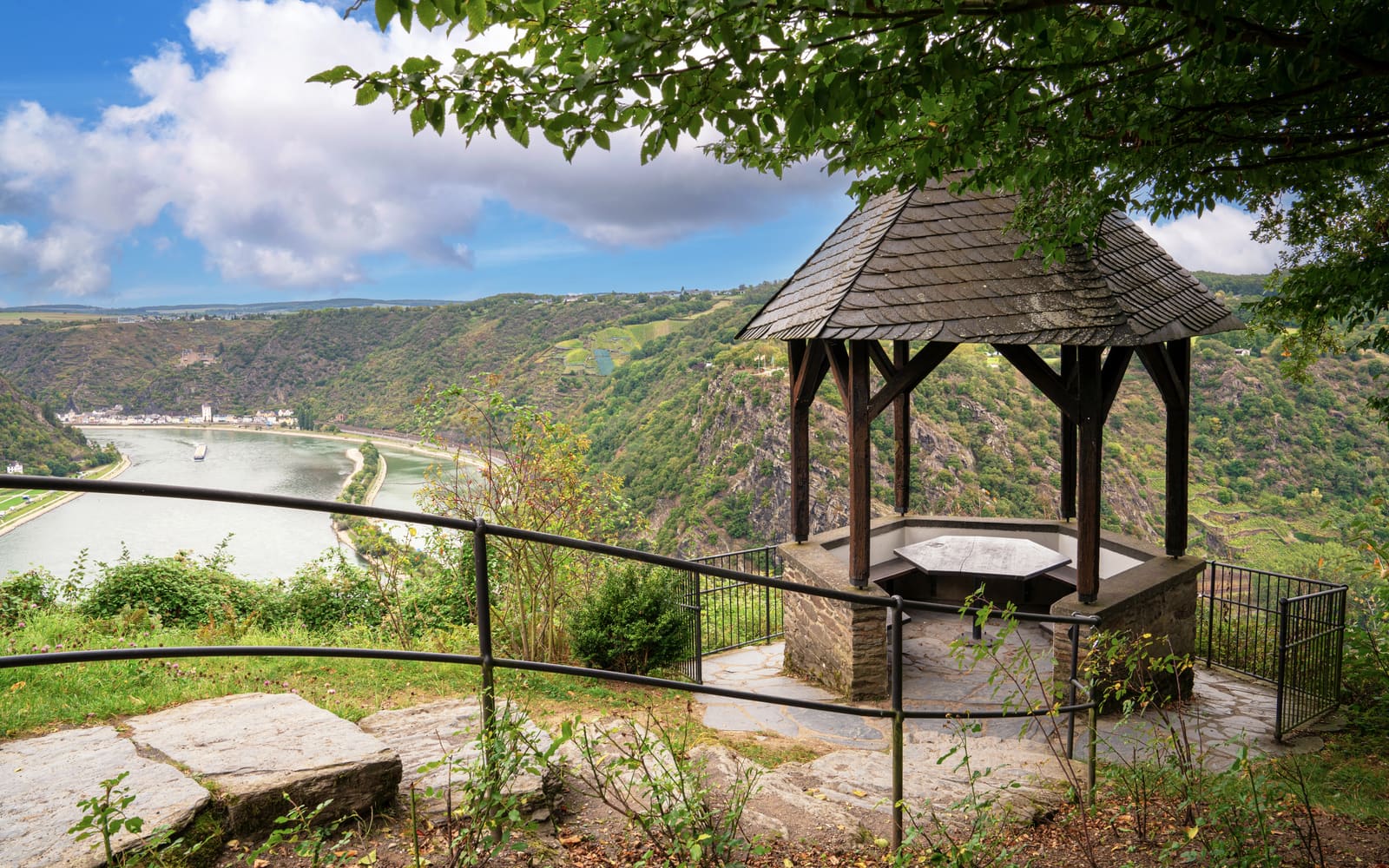 Aussichtspavillon an der Loreley mit Blick auf die enge Rheinschleife, steile Felshänge, Weinberge und ein Frachtschiff