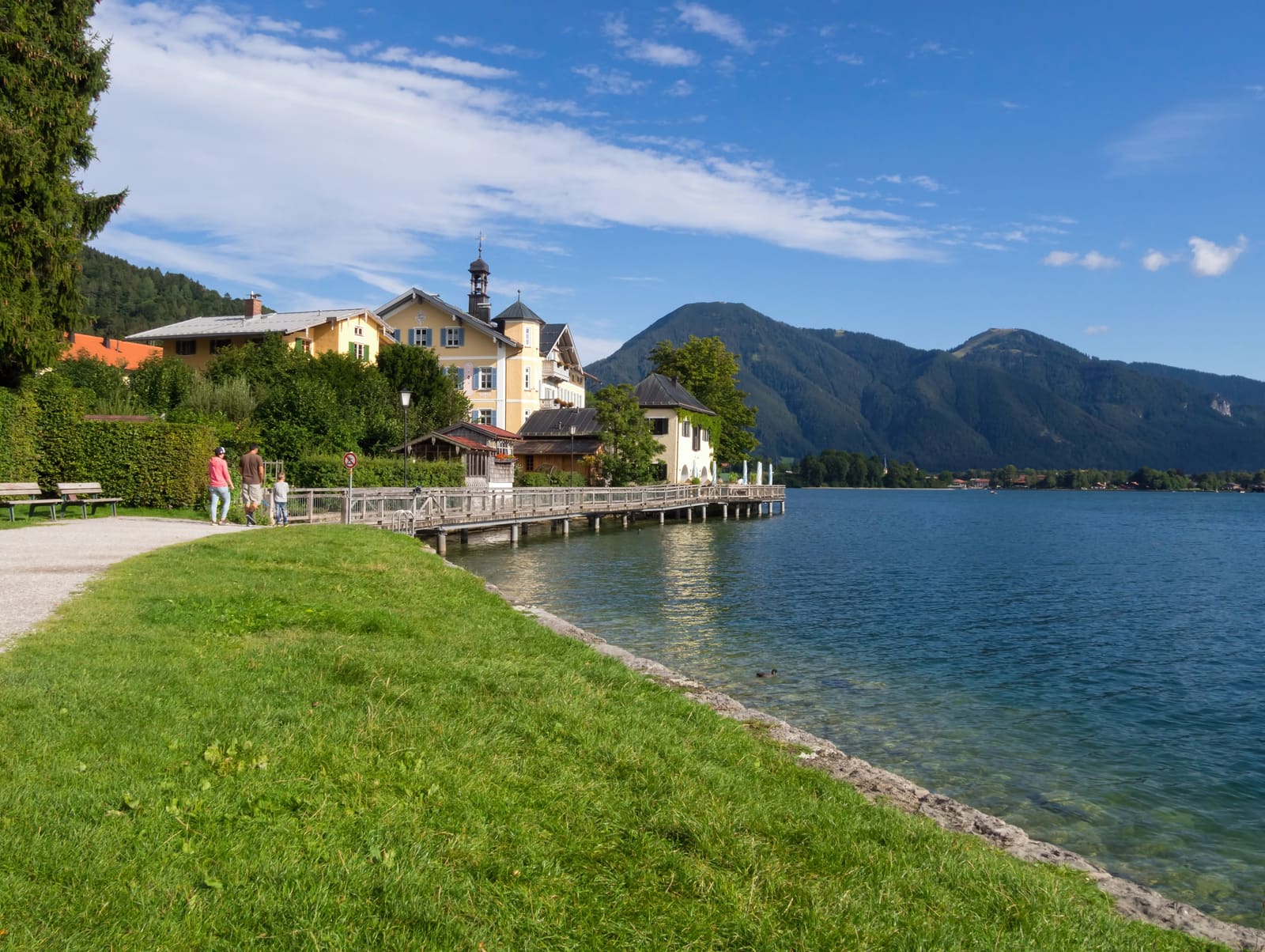 Uferpromenade am Tegernsee mit Liegewiese, Bootssteg, Uferhäusern und bewaldeten Bergen